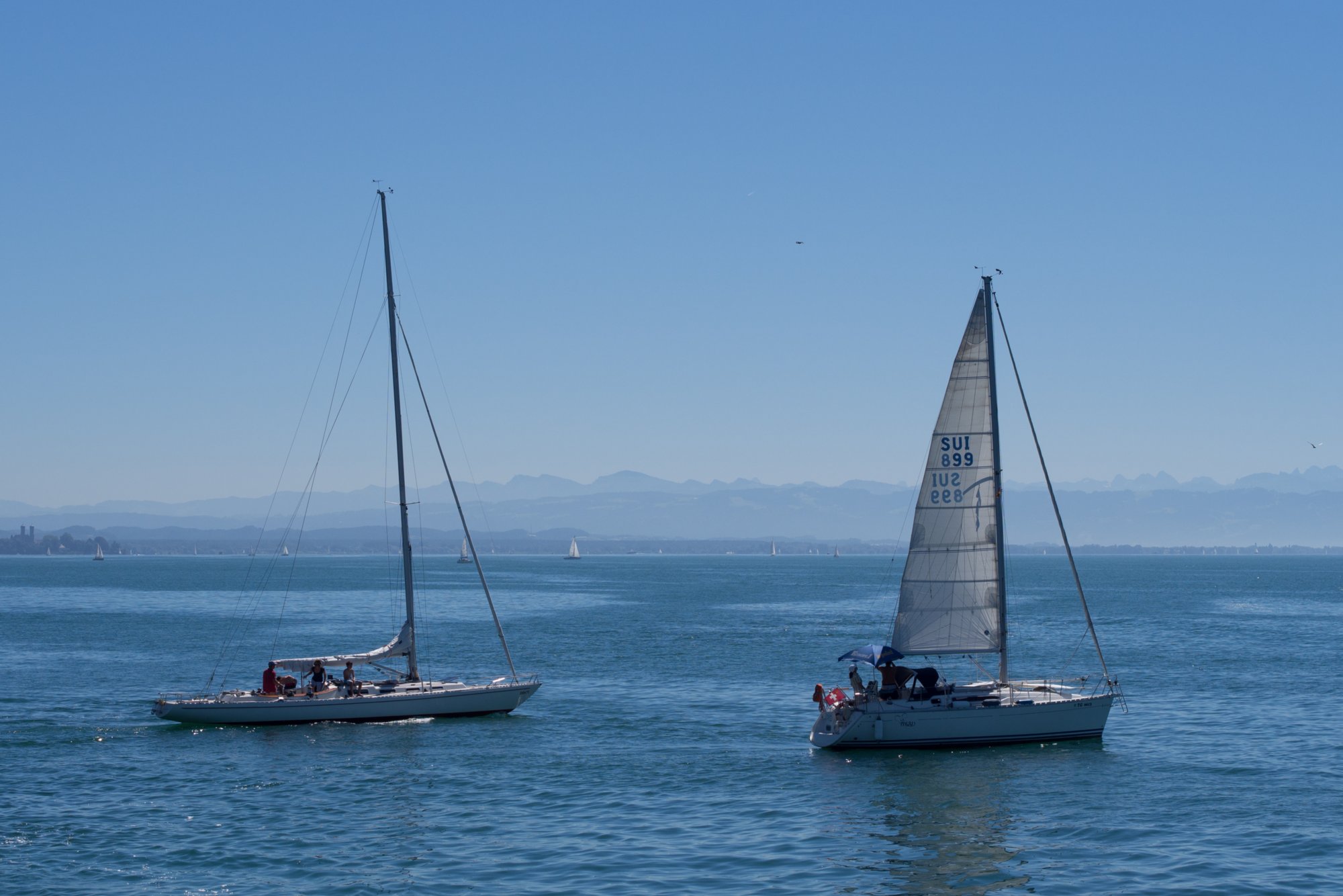 Boote und Blick zu den Bergen Bodenseeschiffahrt: Lindau, Abfahrt in Lindau , Wasserburg, Nonnenhorn, Kressbronn, Langenargen, Friedrichshafen, Immenstaad, Hagnau, Meersburg, Mainau, Einfahrt Konstanz, Stadtbummel durch Konstanz und per Schiff zurück nach Lindau.