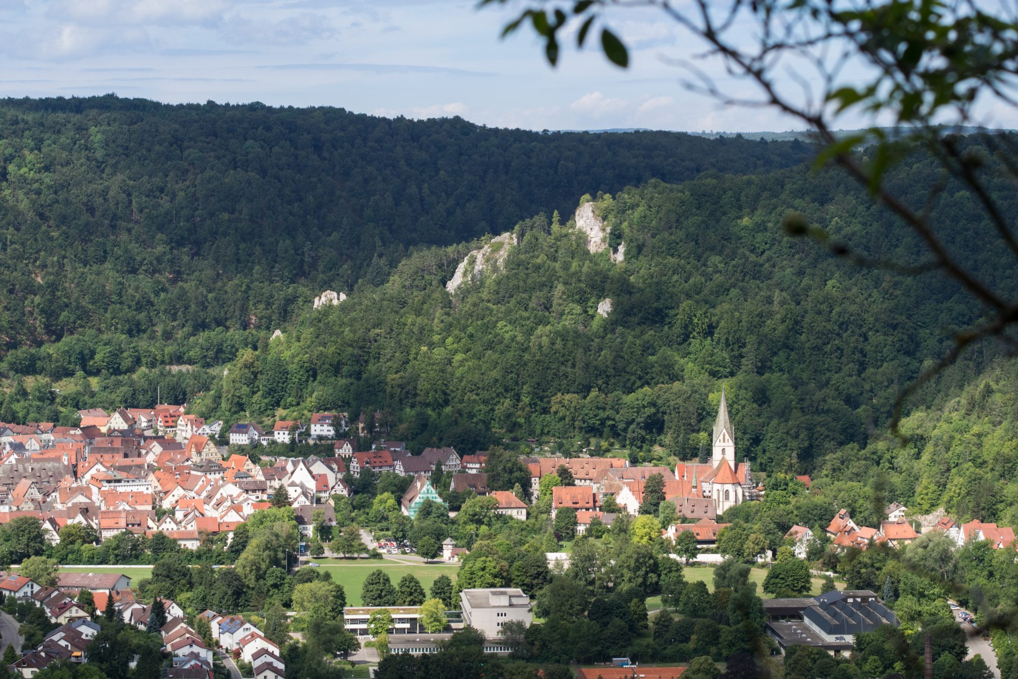 Am Knoblauchfelsen. Blick nach Blaubeuren. Wanderung von Blaubeuren Bahnhof zum Rusenschloss. Von dort über den Knoblauchfelsen zum Blaufelsen. Hinunter zur B28. Diese überquerend Aufstieg auf Teerweg bis zur Steigziegelhütte, da Abzweig nach links zum Landeplatz Seißen nicht gefunden. Entlang am Waldrand zur Wegmarkierung. Dieser folgend zur Günzelburg. Von dort zum Felsenlabyrinth und zur Küssenden Sau. Abstiefg zum Bahnhof. Mit dem Auto zum Blautopf.