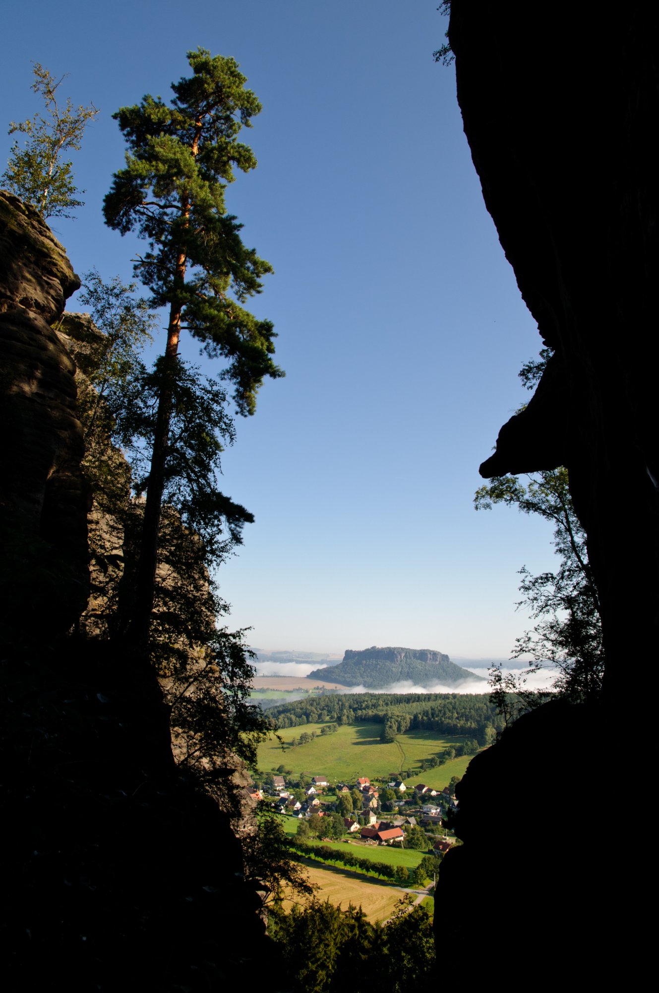 Sächsische Schweiz 2009 Wanderung von Königstein zum Pfaffenstein und wieder zurück nach Königstein. Der schmale und steile Aufstieg zum Pfaffenstein führt über das Nadelöhr. Von Norden erreicht man am schnellsten über das "Nadelöhr" das Plateau. Der Pfad besteht aus rund 600 ungleichmäßig hohen Stufen ist am Ende so eng, dass keine zwei Menschen nebeneinander Platz finden. Auch ist der 1897 erschlossene Pfad gegen Ende so steil, dass der Aufweg mit Eisenleitern erfolgen muss. Dabei durchsteigt man ein horizontales, recht enges Felsloch. Quelle: http://de.wikipedia.org/wiki/Pfaffenstein