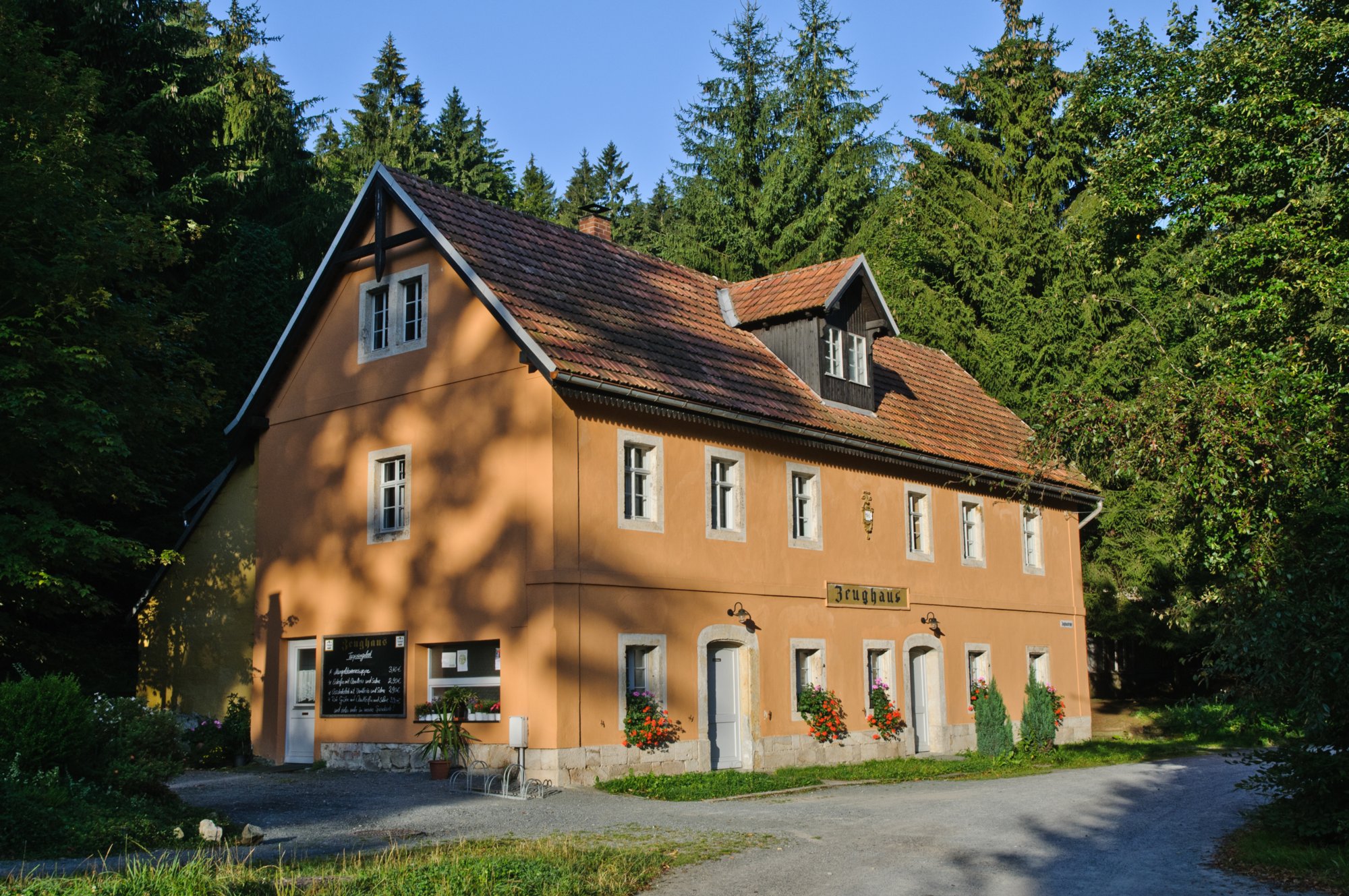 Wanderung zum Hinteren Raubschloß Wanderung über den Goldsteig und den Großen Winterberg zum Hinteren Raubschloss: Neumannssmühle - Zeughaus - Goldsteig - Richtergrotte - Großer Winterberg - Hinteres Raubschloss (Winterstein) - Neumannmühle. Als Zeughaus wird ein altes Forsthaus im Großen Zschand in der Hinteren Sächsischen Schweiz bezeichnet. Es erlangte vor allem dadurch Bekanntheit, dass in unmittelbarer Nähe ein Ferienheim für Mitarbeiter des Ministeriums für Staatssicherheit der DDR errichtet wurde. Erste Ansiedlungen entstanden an dieser Stelle bereits 1642, das heutige Zeughaus wurde um 1870 errichtet. Ein kurfürstlicher Jagdknecht bewahrte hier allerlei Jagdgerät wie Schlingen, Stellnetze, Saufedern, Wolfsspieße, Transportkisten, Hasengarne, Fallen und Wildlappen auf. Erst später entwickelte sich eine zunehmende Gastbewirtung, als um 1900 nach Holzfällern, Fuhrleuten, Deserteuren und Schmugglern nun auch die ersten Touristen die Gegend bevölkerten. Auch das gesamte Areal profitierte von diesem ersten Ansturm, denn ein sich niederlassender Förster ließ rund um das Zeughaus eine kleine Siedlung entstehen. Die Grenznähe des Geländes machte in den dreißiger Jahren sogar ein Zollhaus unabdingbar. Zu DDR-Zeiten wurden schließlich 30 vornehme Ferienwohnungen für Mitarbeiter des Ministeriums für Staatssicherheit gebaut. 1974 wurde das Alte Zeughaus geschlossen und Besucher der Gegend mussten von da an mit einer biergartenähnlichen Freilufteinrichtung vorlieb nehmen. Diese Bewirtschaftung wurde in den neunziger Jahren eingestellt und der Herbergenbetrieb im ehemaligen Stasiheim wurde 1996 beendet. Der Freistaat Sachsen bemühte sich um eine Ausschreibung des Geländes und erst im Mai 2000 konnte das herunter gekommene Areal verkauft werden. Vertragsinhalt war unter anderem eine Sanierung des Zeughauses und ein Abriss der DDR-Bauten, so dass zum heutigen Tage wieder eingekehrt werden kann. Die Bauten des Ferienheims sind inzwischen komplett abgerissen worden, an ihrer Stelle f